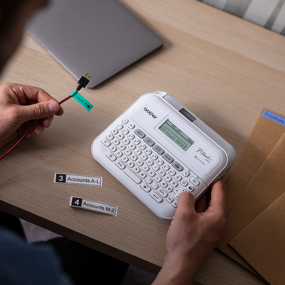 Rotuladora Brother PT-D410 en escritorio imprimiendo cintas para cables