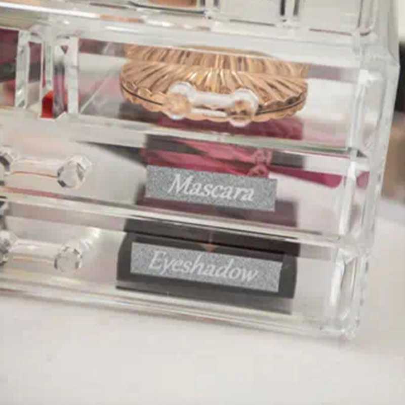 Recipiente de acrílico para guardar maquillajes, etiquetado con cintas adhesivas TZE-PR953 color plateado para indicar el contenido de cada cajón de forma elegante y práctica.