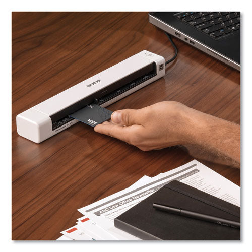 Escáner Brother modelo DS-640 sobre un escritorio de madera, escaneando una tarjeta de crédito VISA