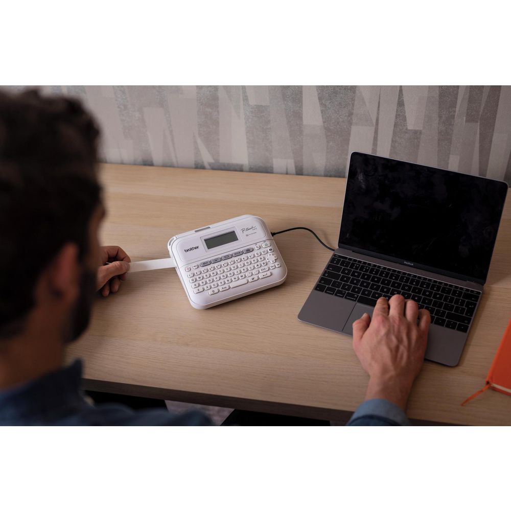 Joven ejecutivo imprimiendo una etiqueta adhesiva desde su notebook, usando la rotuladora brotrher modelo PT-D410.